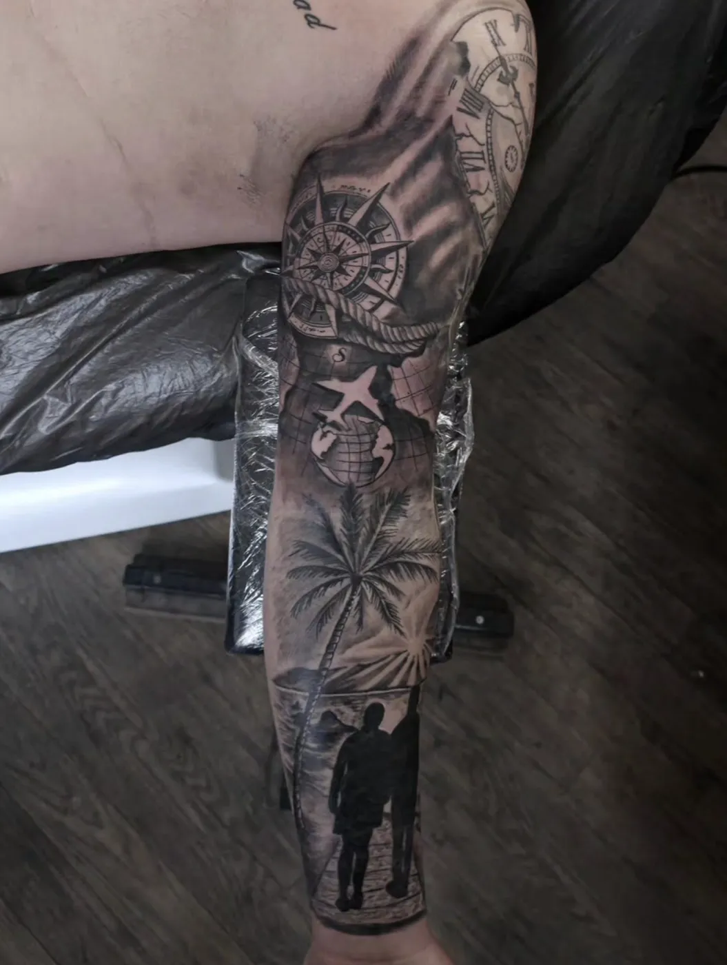Reise-Themen-Sleeve mit Kompass, Uhr, Flugzeug, Globus und Palme am Arm.