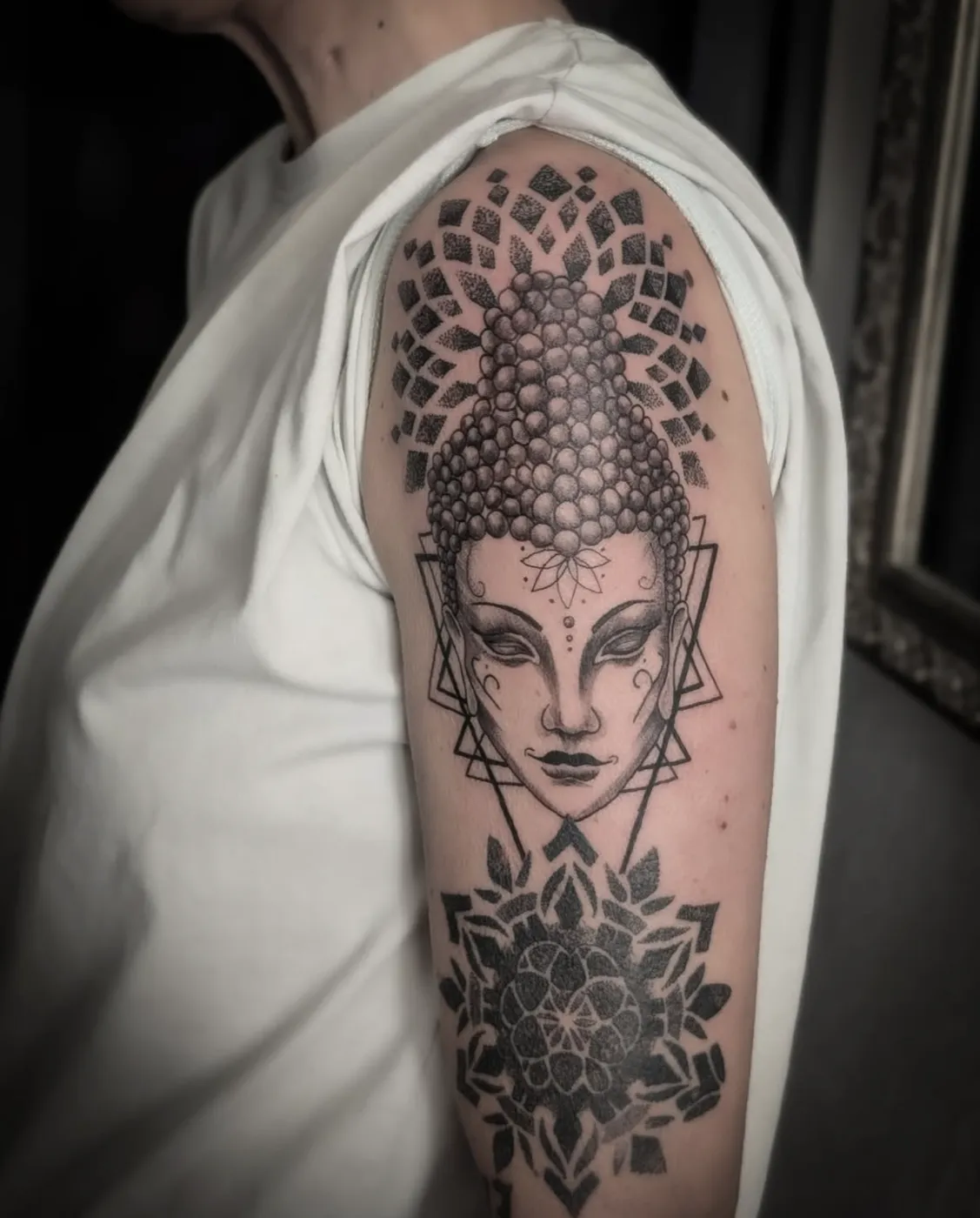 Meditatives Buddha-Portrait mit Mandala-Elementen in Dotwork auf dem Oberarm.